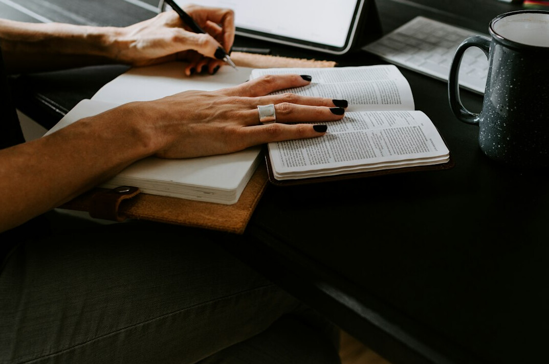 person writing in journal at desk